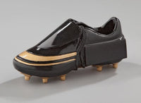 Thumbnail for Ein schwarzer Schuh mit goldenen Akzenten, mit dickem Absatz und Nieten wie bei einem Fußballschuh, vor einem neutralen Hintergrund. Dieses aus hochwertigem Material gefertigte Einzelstück ist ein echter Trophäe-Fußballschuh 130x55 mm PK738665-62588 und sticht in jeder Sammlung hervor.